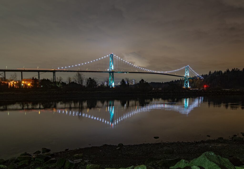 A night time photo of Lions Gate Bridge from the banks of the Capilano river in British Columbia